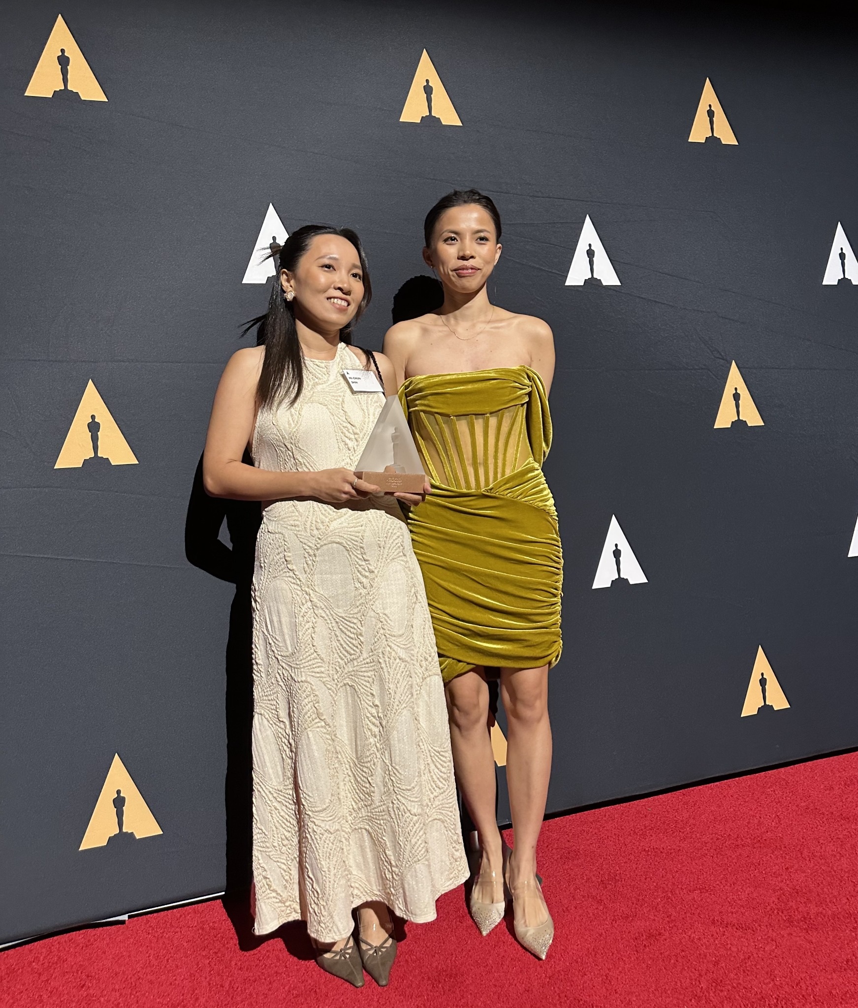 Two members of the I Remember team holding an award on the Student Academy Awards red carpet.